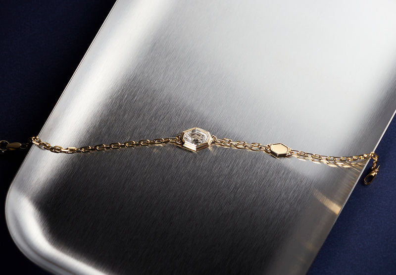 Signature LEIL 18k yellow gold chain station bracelet with a spike lab diamond on a metallic surface