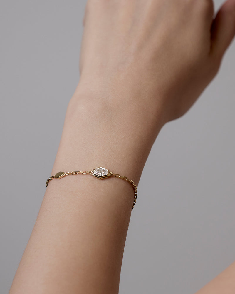 Gold bracelet with a spike lab diamond on a wrist against a neutral background