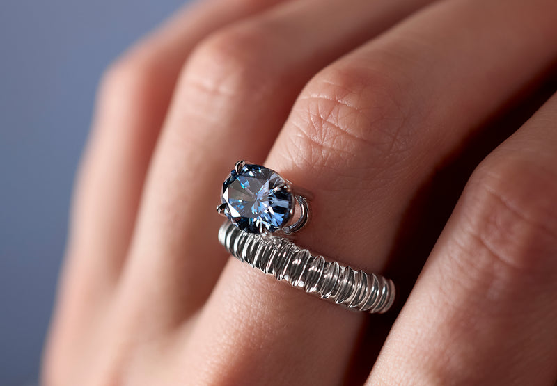 Signature LEIL architectural ring in 18k white gold with a large blue oval diamond on a hand against a neutral background