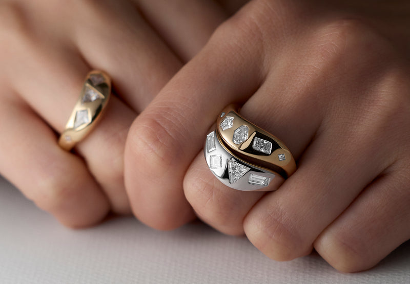Close-up of hands wearing stacks of signature LEIL 18k yellow and white gold rings with cluster lab diamond accents on a neutral background