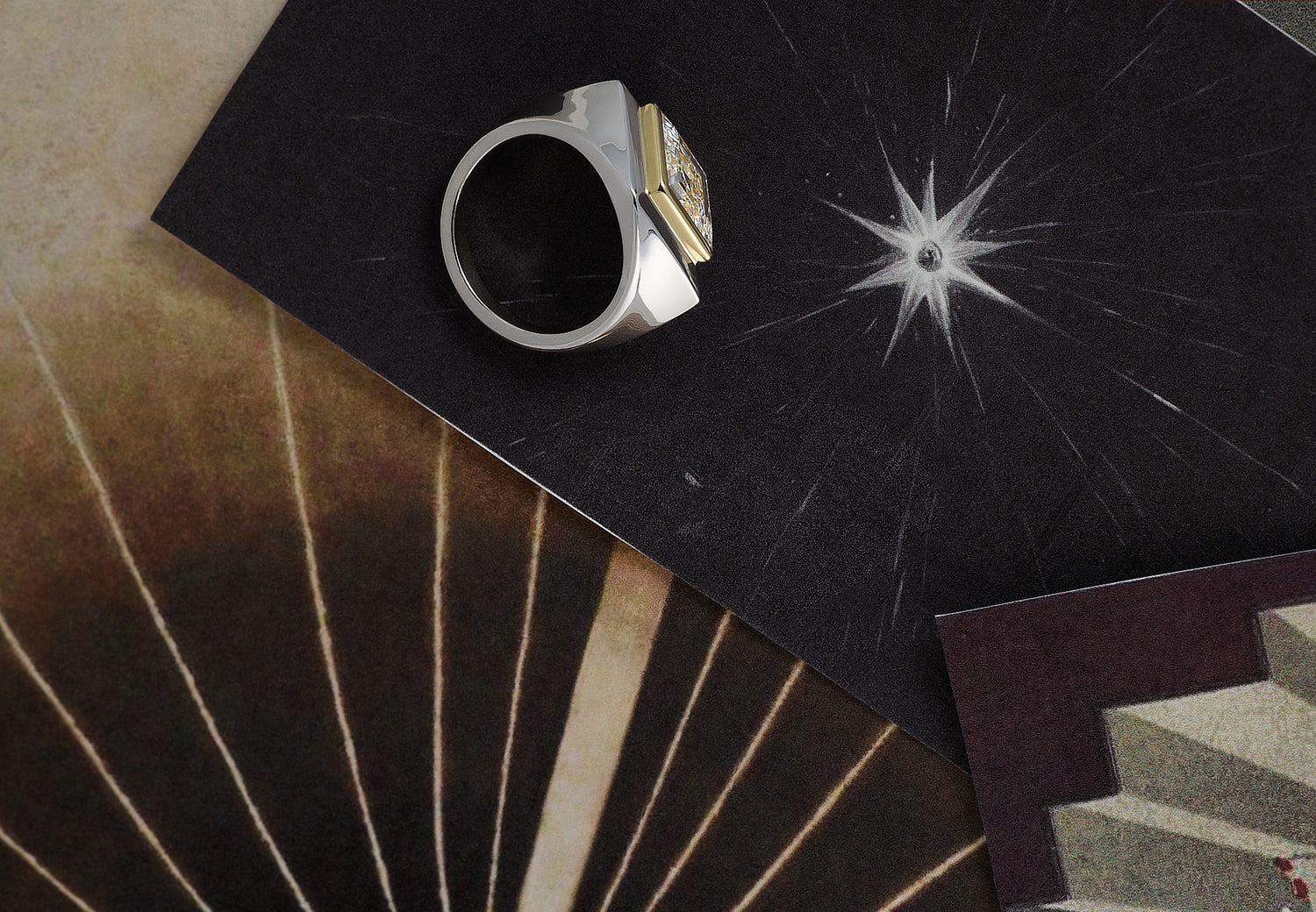 A Leil solid white gold and yellow gold ring with double bezel, a signet ring with a lozenge lab grown diamond on a black textured surface, surrounded by patterned drawings of light reflections.